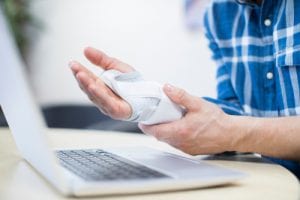 person with hurt hand in front of computer