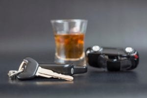 car keys, rolled over toy car and alcoholic drink