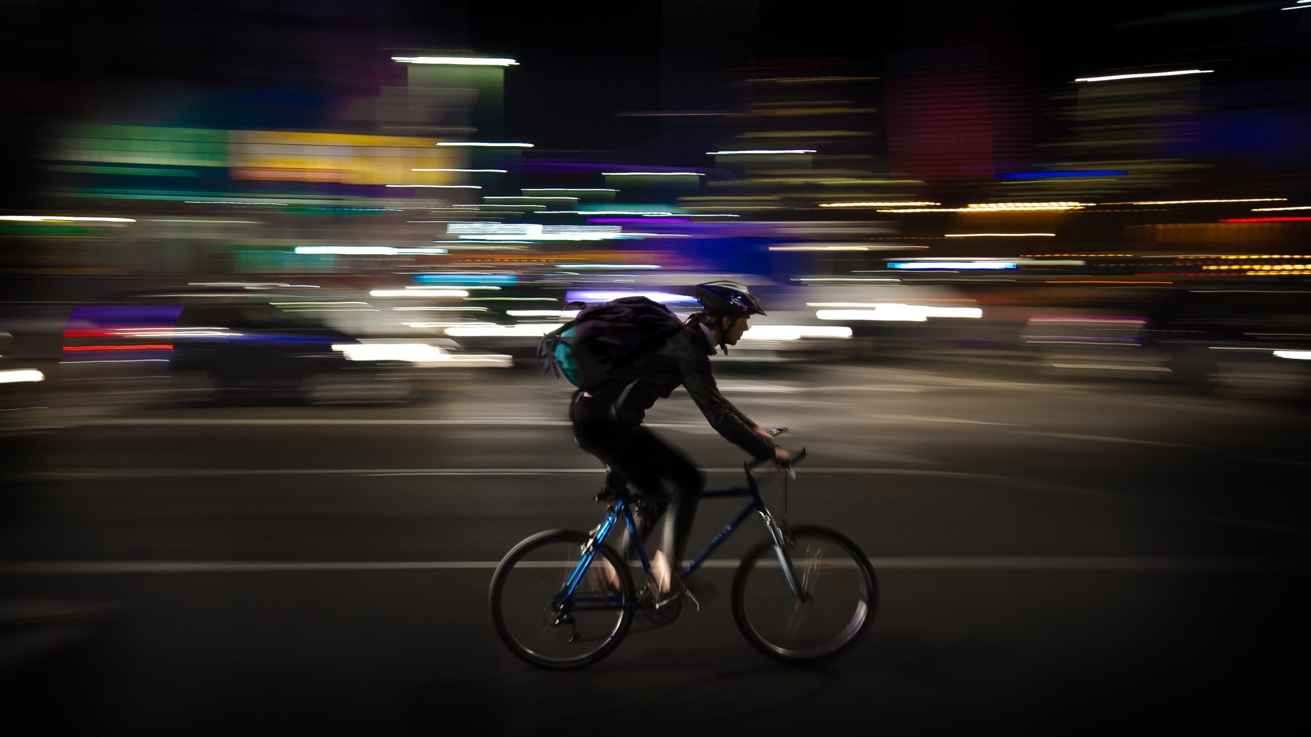 man racing bike through the city at night