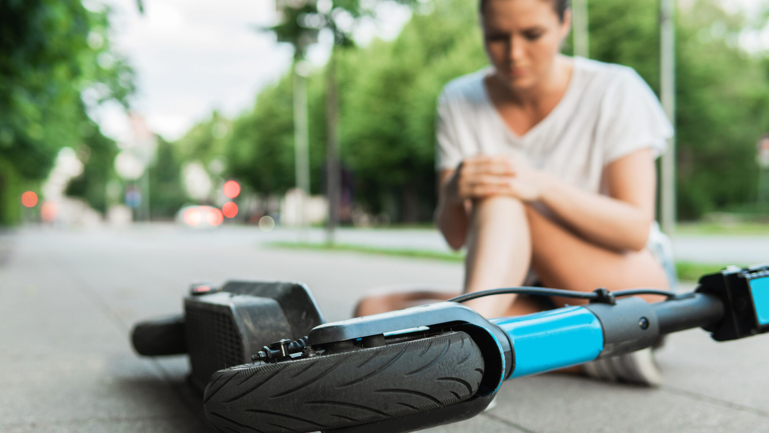 Woman holding injured knee, exemplifying the common injuries seen by electric scooter accident lawyers.