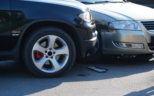 two cars stopped after a front end collision with a phone on the ground