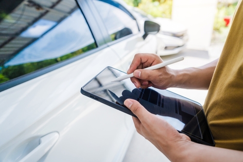 Person documenting vehicle damage on a tablet after a Rideshare Crash in NYC.