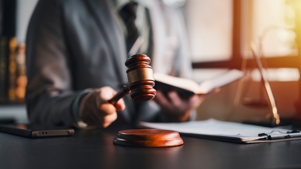 An attorney is reading a book while holding a gavel. Focus on auction legal lawyer judge courthouse trial business concept law court justice system.